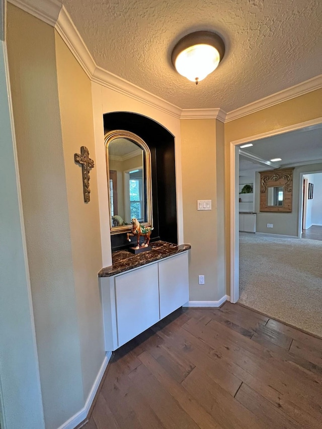 hallway with a textured ceiling, dark hardwood / wood-style floors, and ornamental molding