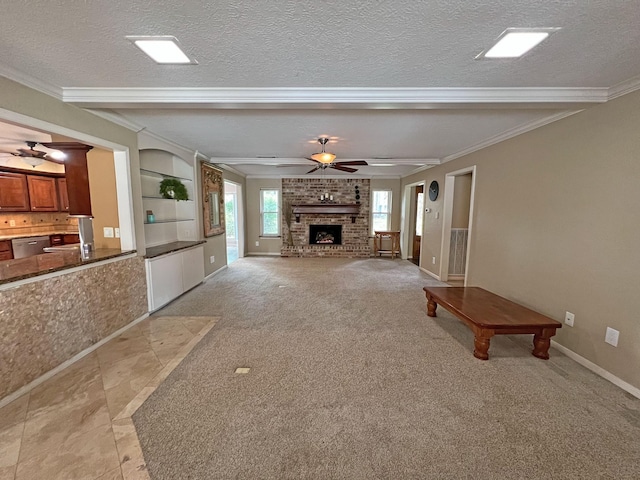 unfurnished living room with a textured ceiling, a brick fireplace, ceiling fan, and crown molding