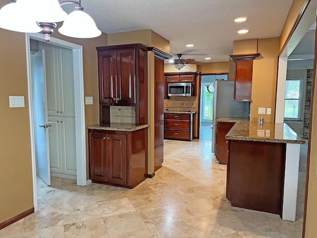 kitchen featuring pendant lighting, ceiling fan, light stone counters, kitchen peninsula, and stainless steel appliances