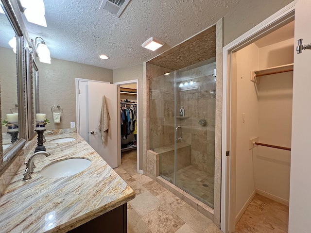 bathroom with vanity, a textured ceiling, and a shower with door