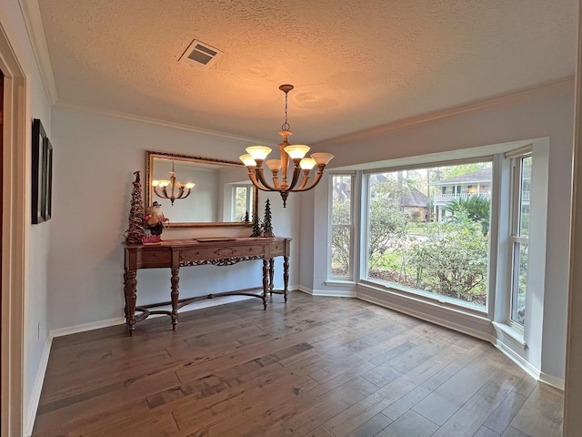 dining room featuring hardwood / wood-style floors, a notable chandelier, ornamental molding, and a textured ceiling