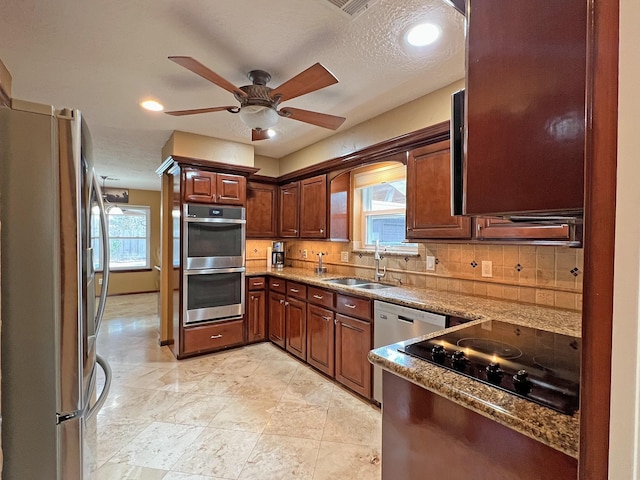 kitchen featuring appliances with stainless steel finishes, tasteful backsplash, plenty of natural light, and sink