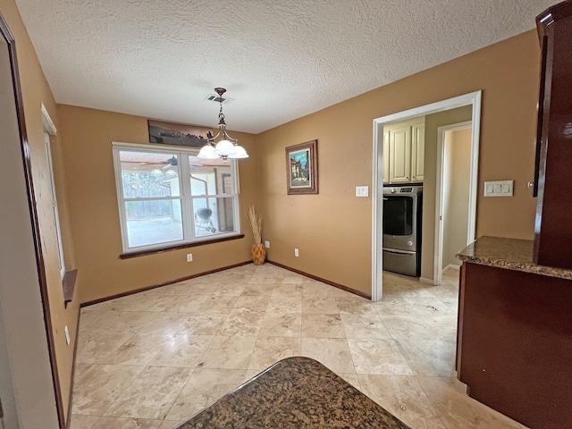 unfurnished dining area featuring a chandelier, a textured ceiling, and washer / dryer