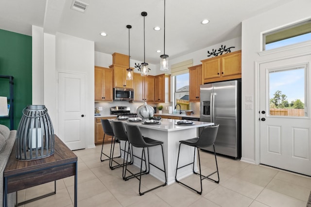 kitchen featuring a center island, hanging light fixtures, a breakfast bar area, light tile patterned floors, and stainless steel appliances