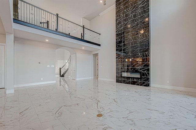 unfurnished living room with a large fireplace and a towering ceiling