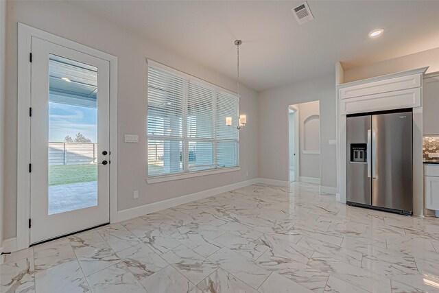 kitchen with white cabinets, pendant lighting, stainless steel fridge, and a chandelier