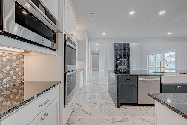 kitchen with sink, white cabinets, stainless steel appliances, and dark stone countertops