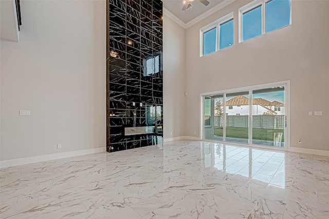 unfurnished living room with crown molding and a towering ceiling