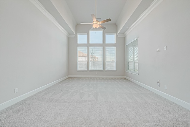 unfurnished room featuring ceiling fan, light carpet, crown molding, and a high ceiling