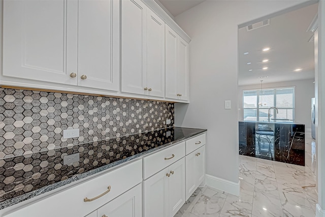 kitchen with tasteful backsplash, white cabinets, and dark stone countertops