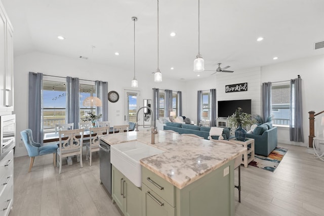 kitchen featuring a breakfast bar, ceiling fan, sink, and an island with sink