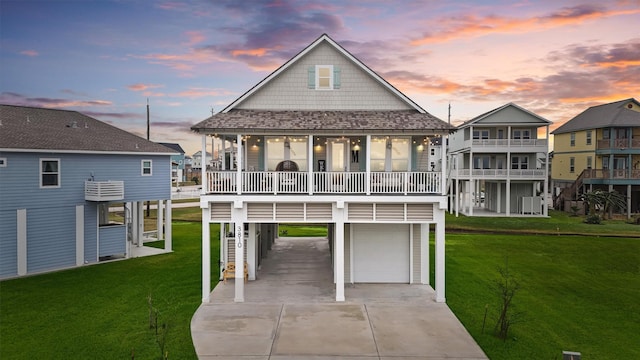 back house at dusk featuring a lawn, a carport, and a garage