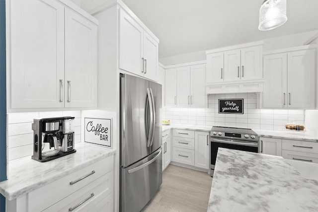 kitchen with white cabinets, hanging light fixtures, appliances with stainless steel finishes, tasteful backsplash, and light stone counters