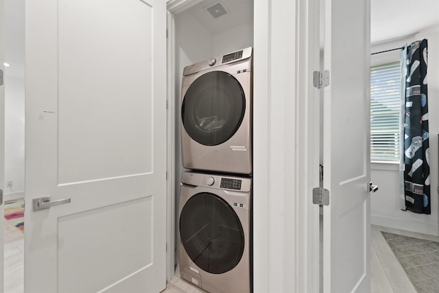 clothes washing area with light tile patterned floors and stacked washer / dryer