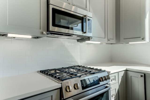 kitchen featuring gray cabinets, backsplash, and appliances with stainless steel finishes