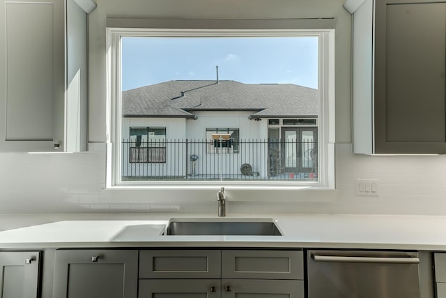 kitchen with gray cabinets, a wealth of natural light, sink, and stainless steel dishwasher