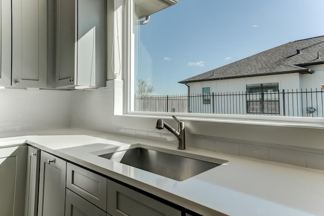 kitchen with backsplash, gray cabinets, and sink