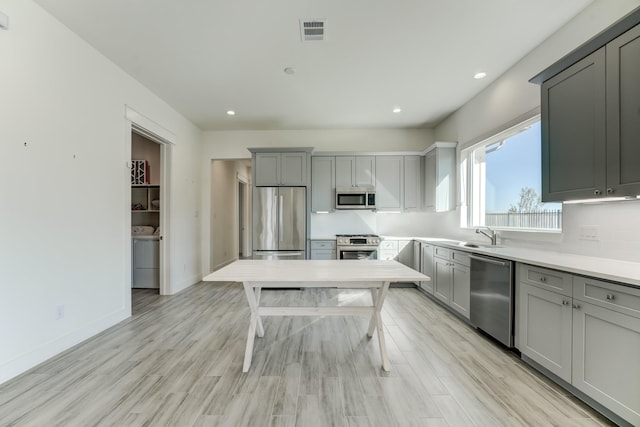 kitchen featuring gray cabinets, sink, light wood-type flooring, and stainless steel appliances