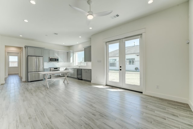 kitchen with gray cabinets, french doors, appliances with stainless steel finishes, and light hardwood / wood-style flooring