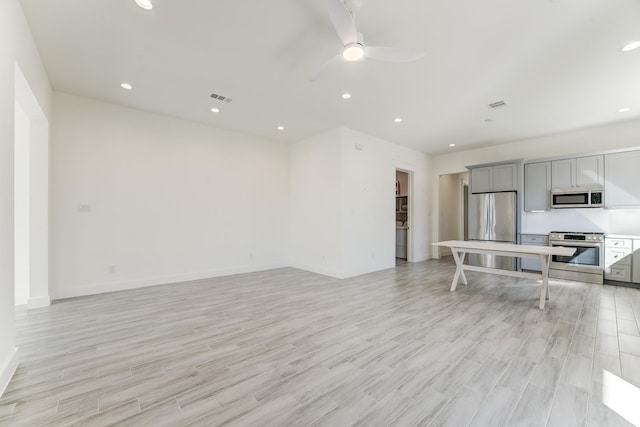 kitchen with stainless steel appliances, gray cabinets, ceiling fan, and light hardwood / wood-style floors