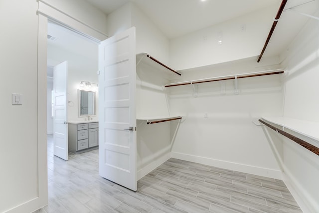 walk in closet with sink and light hardwood / wood-style floors