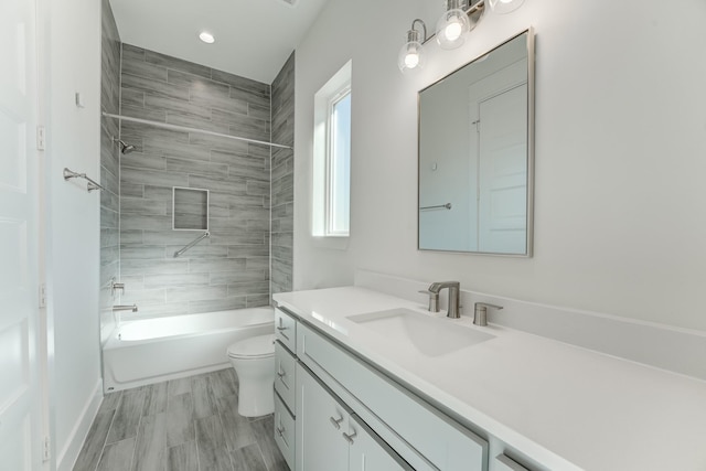 full bathroom featuring hardwood / wood-style flooring, vanity, toilet, and tiled shower / bath