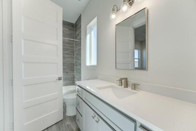 full bathroom with vanity, hardwood / wood-style flooring, toilet, and tiled shower / bath