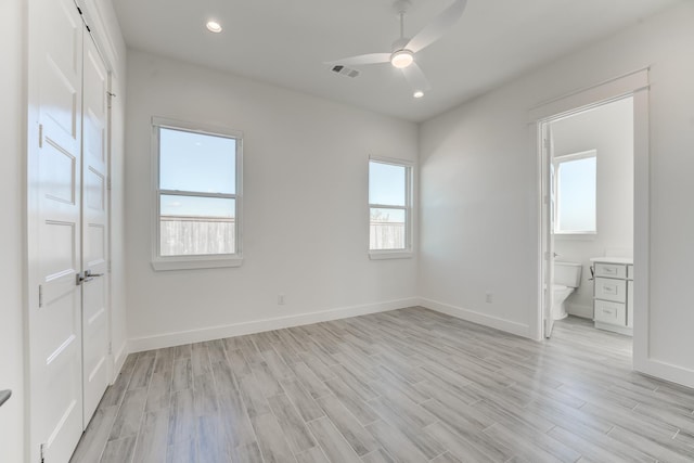 unfurnished bedroom featuring connected bathroom, light hardwood / wood-style floors, multiple windows, and ceiling fan