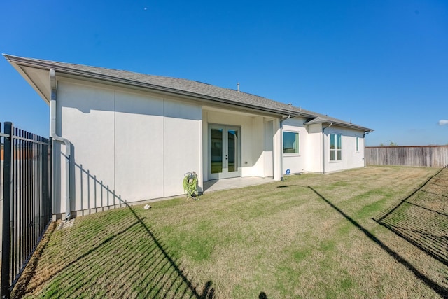 back of property with a lawn and french doors