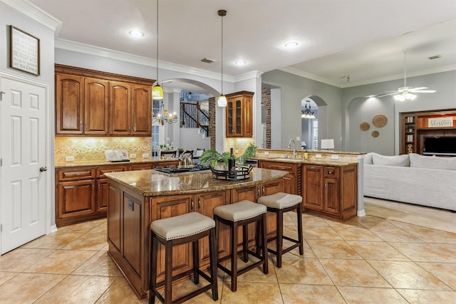 kitchen featuring hanging light fixtures, kitchen peninsula, a breakfast bar, ceiling fan with notable chandelier, and ornamental molding