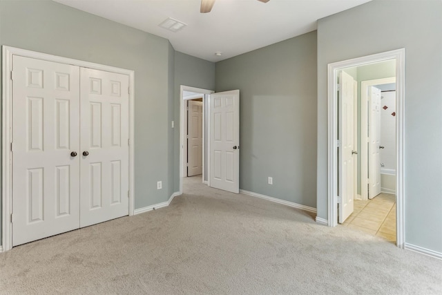 unfurnished bedroom with ensuite bath, ceiling fan, a closet, and light colored carpet