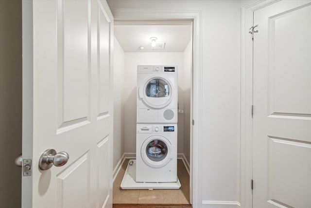 laundry room featuring stacked washer and dryer and tile patterned flooring