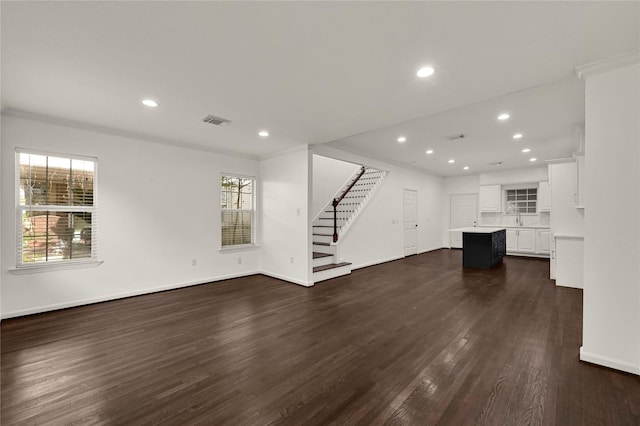 unfurnished living room with dark hardwood / wood-style flooring, plenty of natural light, and ornamental molding