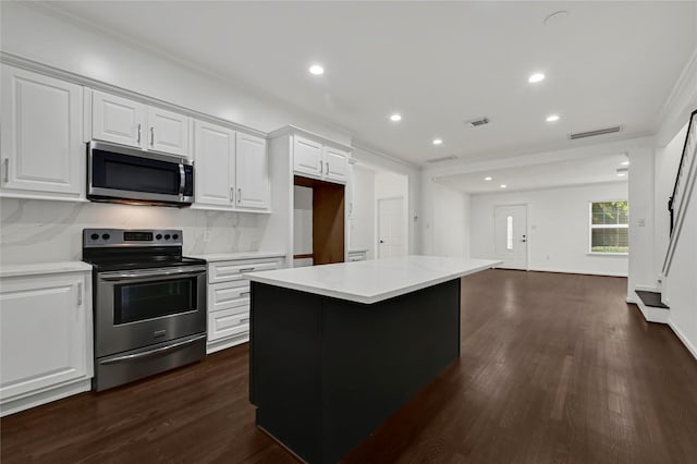 kitchen featuring white cabinets, a kitchen island, stainless steel appliances, and dark wood-type flooring