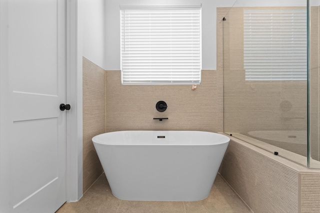 bathroom with a washtub, tile walls, and tile patterned flooring