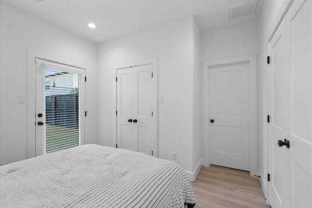 bedroom featuring access to exterior, light wood-type flooring, and multiple windows