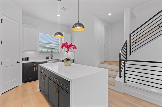 kitchen with pendant lighting, sink, tasteful backsplash, a kitchen island, and white cabinetry