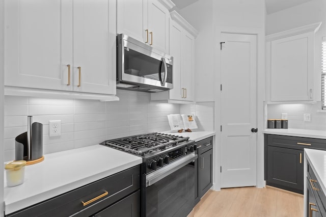 kitchen with white cabinetry, backsplash, and appliances with stainless steel finishes