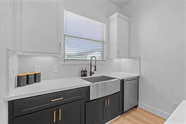 kitchen with stainless steel dishwasher, white cabinetry, sink, and tasteful backsplash