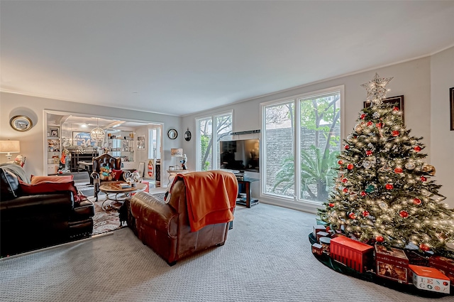 living area with carpet floors, a glass covered fireplace, and crown molding