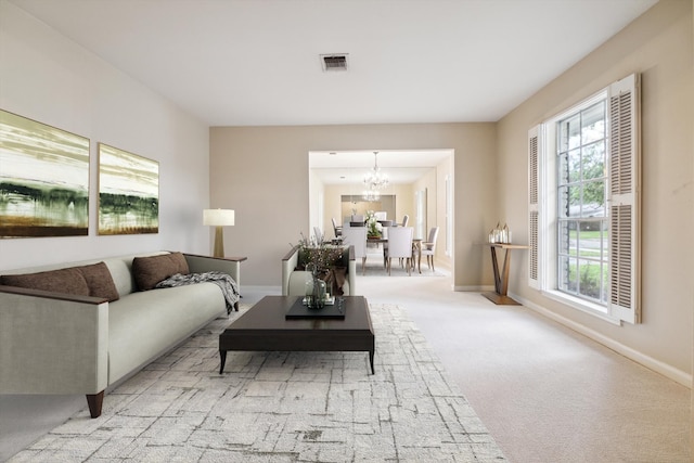 carpeted living room featuring an inviting chandelier