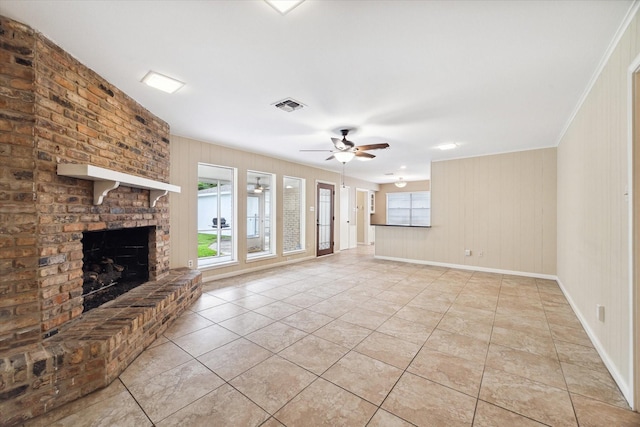 unfurnished living room with ceiling fan, light tile patterned flooring, ornamental molding, and a brick fireplace