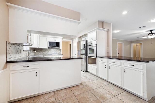 kitchen with kitchen peninsula, appliances with stainless steel finishes, white cabinetry, and sink