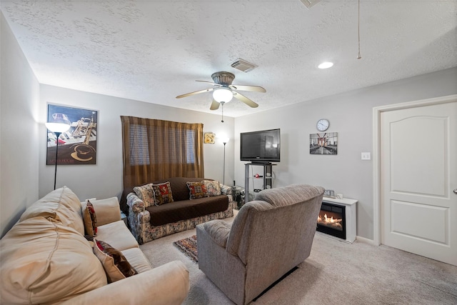 living room featuring ceiling fan, light colored carpet, and a textured ceiling