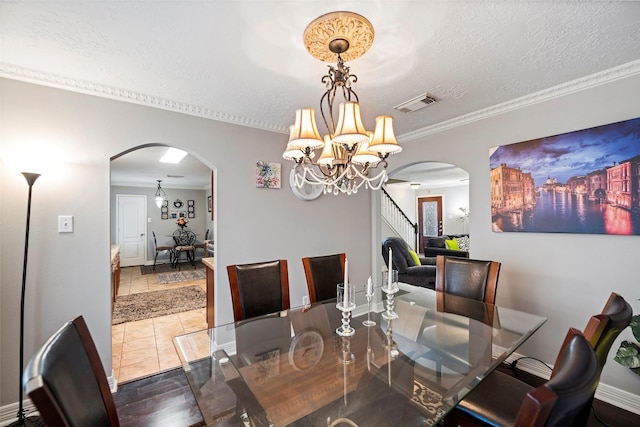 dining space with a textured ceiling, a notable chandelier, wood-type flooring, and crown molding