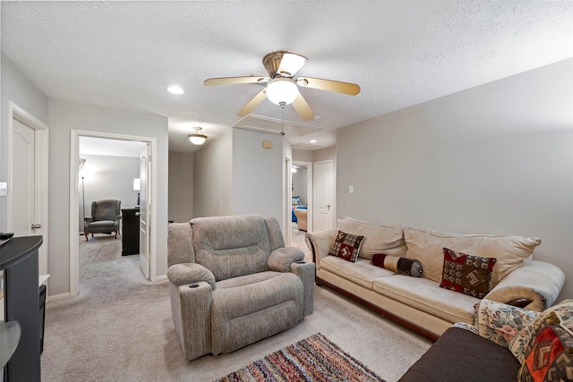 living room featuring light carpet, ceiling fan, and a textured ceiling