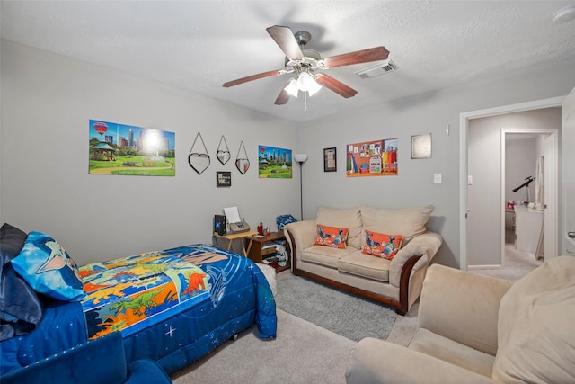 carpeted bedroom with ceiling fan and a textured ceiling