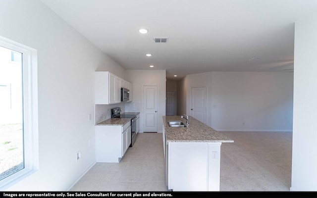 kitchen with black electric range, white cabinets, plenty of natural light, and sink