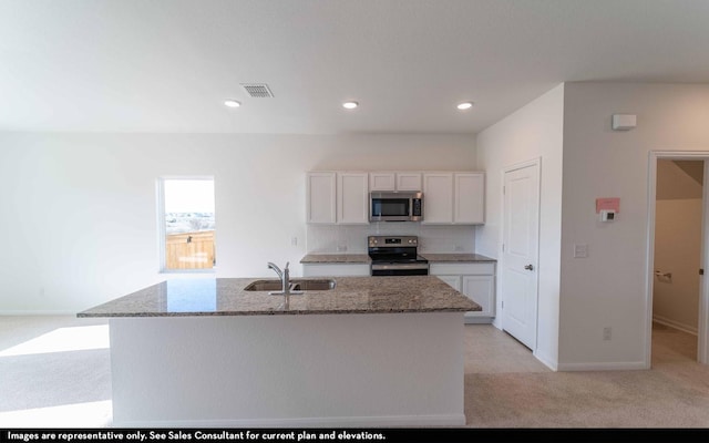 kitchen with a kitchen island with sink, light carpet, sink, appliances with stainless steel finishes, and white cabinetry