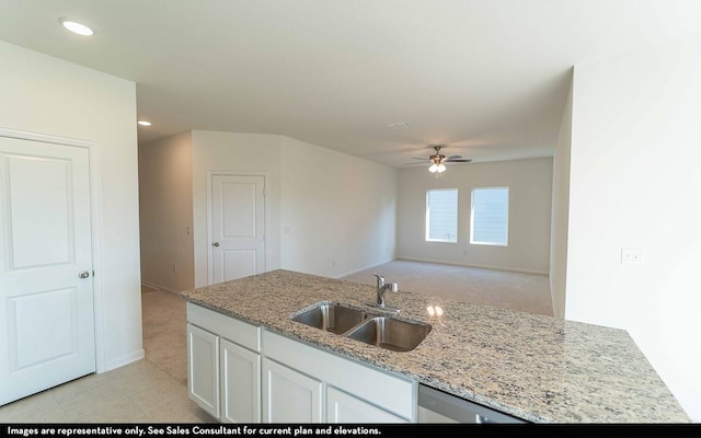 kitchen with ceiling fan, light stone counters, white cabinetry, and sink